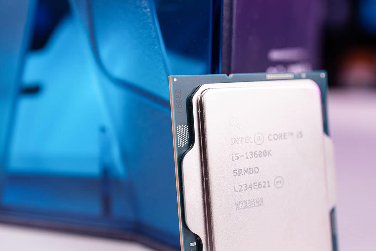Close-up of an Intel Core i5-13600K processor in focus, with a blurred blue computer case in the background.