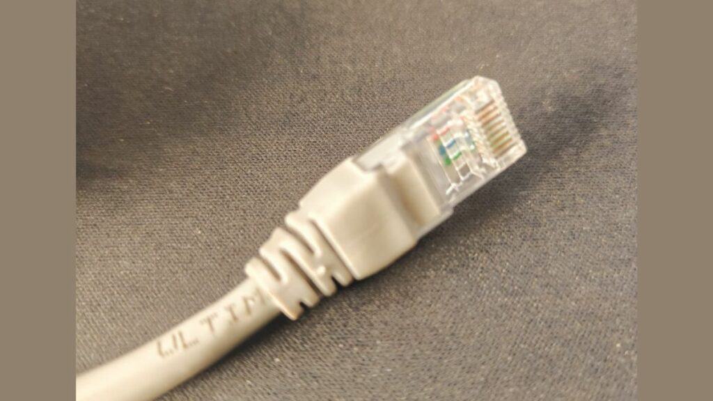 RJ45 ethernet cable plug connector on a gray background.
