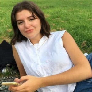 About Us: A young woman enjoying a relaxing moment on the grass, using her cell phone.