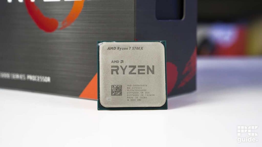 An AMD Ryzen 7 5700X CPU positioned in front of its product packaging with a blurred background.