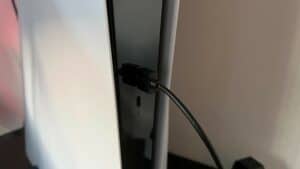 A close up of a tv with a cable connected to it, ready to connect a PS5 controller.
