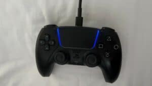 Connect a black PlayStation controller on a white bed.