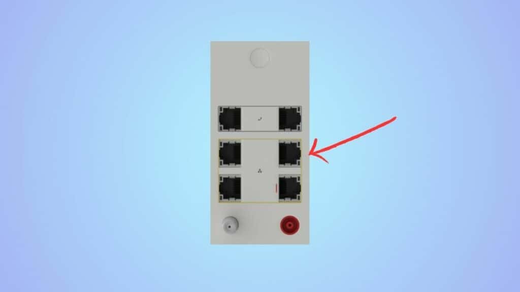Ethernet wall plate with four ports and a red reset button, highlighted by a blinking orange arrow pointing at one of the ports.