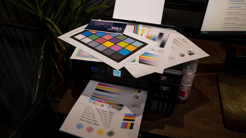 An Epson EcoTank ET-2850, an all-in-one printer, sitting on a home desk with papers on top of it.