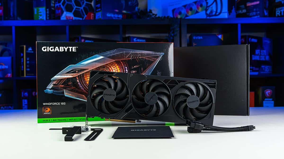 Gigabyte RTX 4080 Super graphics card with box and accessories displayed on a desk with colorful PC hardware in the background.