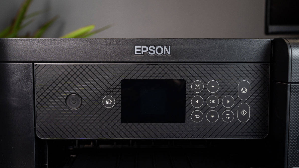 The Epson EcoTank ET-2850, an all-in-one printer, is sitting on a table next to a plant in a home.