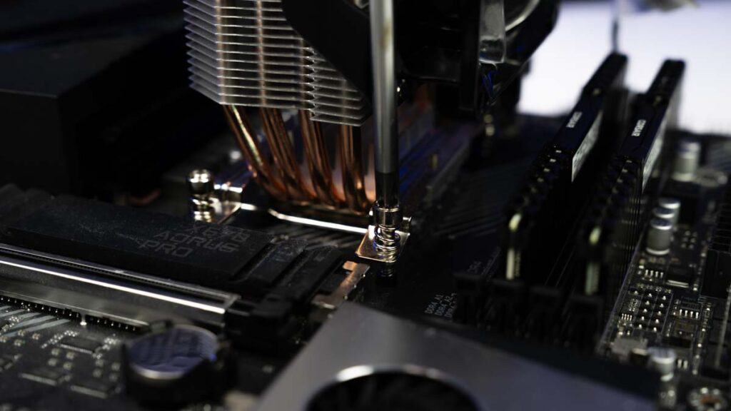 Close-up of a computer motherboard with a mounted CPU cooler, highlighting detailed components and copper heat pipes, ideal for learning how to apply thermal paste to a CPU.