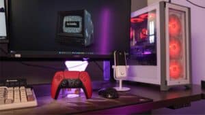 A gaming setup featuring a red DualSense controller, keyboard, and a white desktop pc with red led fans.