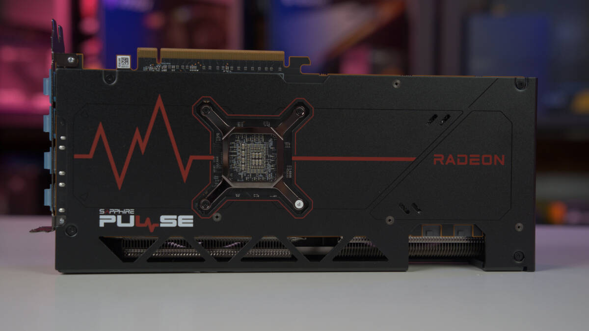 A review of the AMD Radeon RX 7700 XT graphics card lying horizontally with its backplate visible against a blurred background, showcasing why it's worth it.