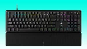 Backlit Corsair K70 mechanical gaming keyboard with wrist rest on a teal background.