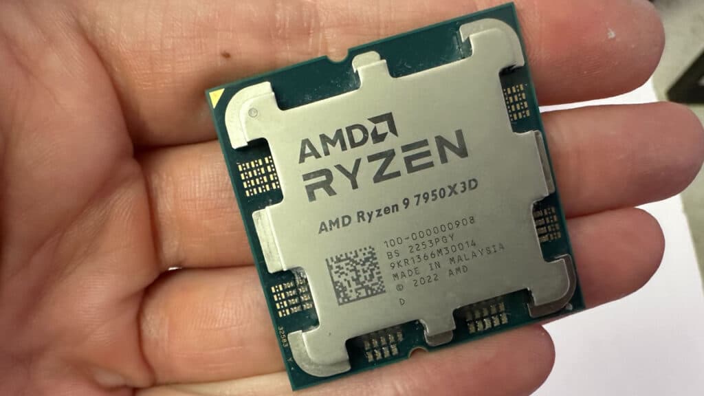 A hand holding an AMD Ryzen 9 7950X3D CPU, showcasing its worth it stature according to reviews.