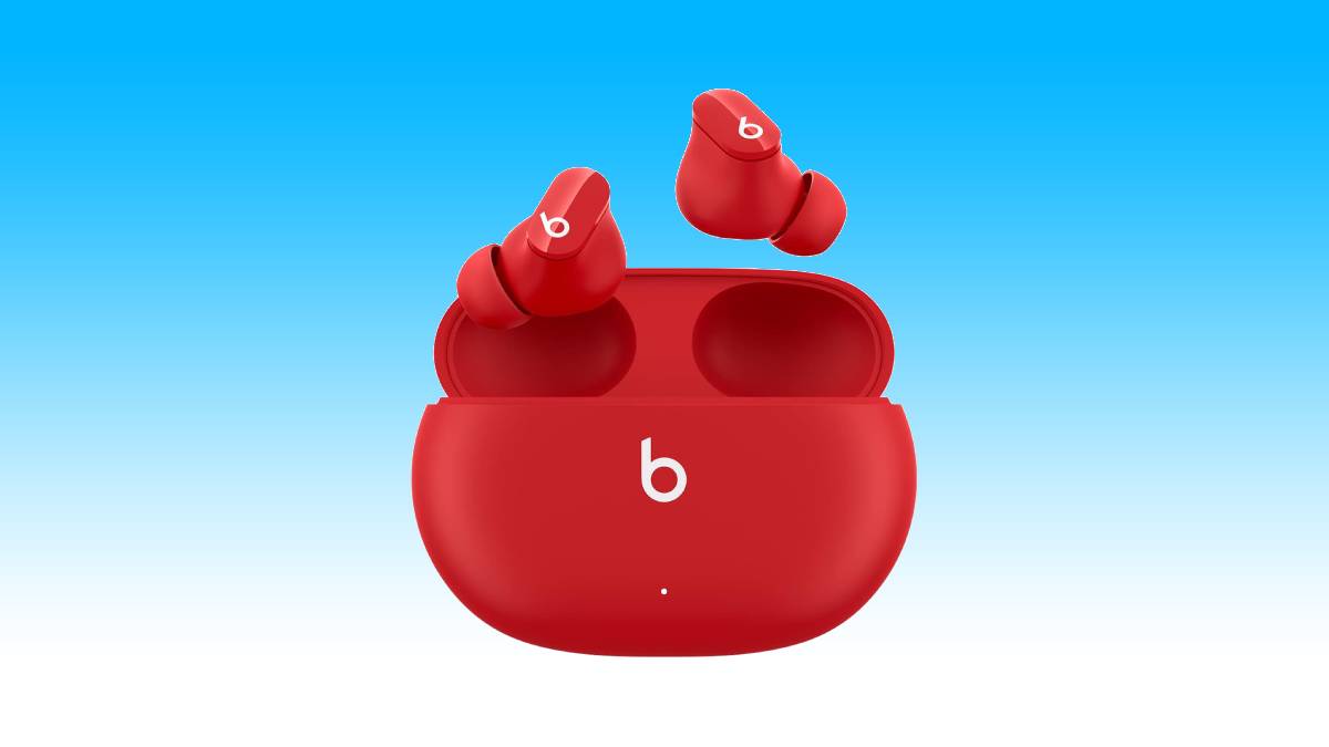 Red Beats Studio Buds with matching charging case against a blue background, featuring noise-canceling technology.
