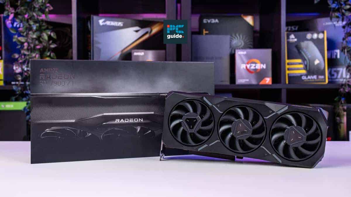 Best AMD Radeon RX 7900 XT graphics card displayed in front of its box with PC components in the background.