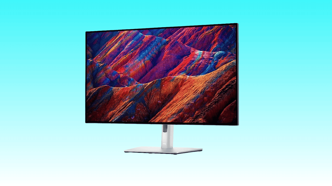 A modern 4K monitor displaying a vibrant, colorful image of mountainous terrain on a solid light blue background.