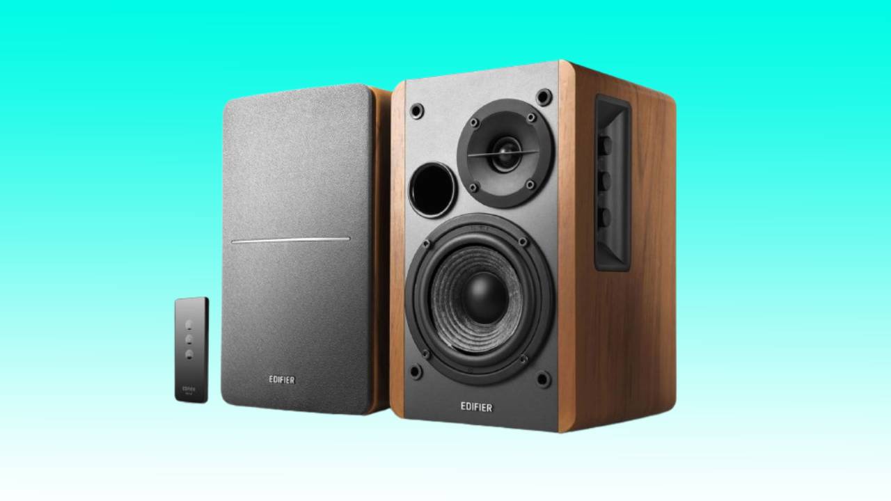 A pair of Edifier bookshelf speakers with a remote control on a turquoise background, offering the best deal for gaming PC audio upgrade.