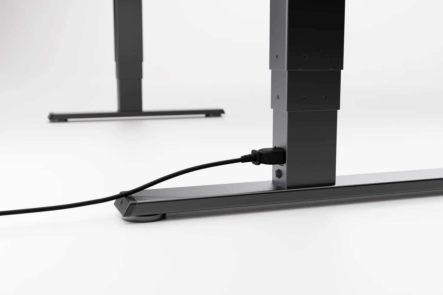 A power cord neatly running through a cable management clip attached to the leg of a Secretlab Magnus Pro desk.