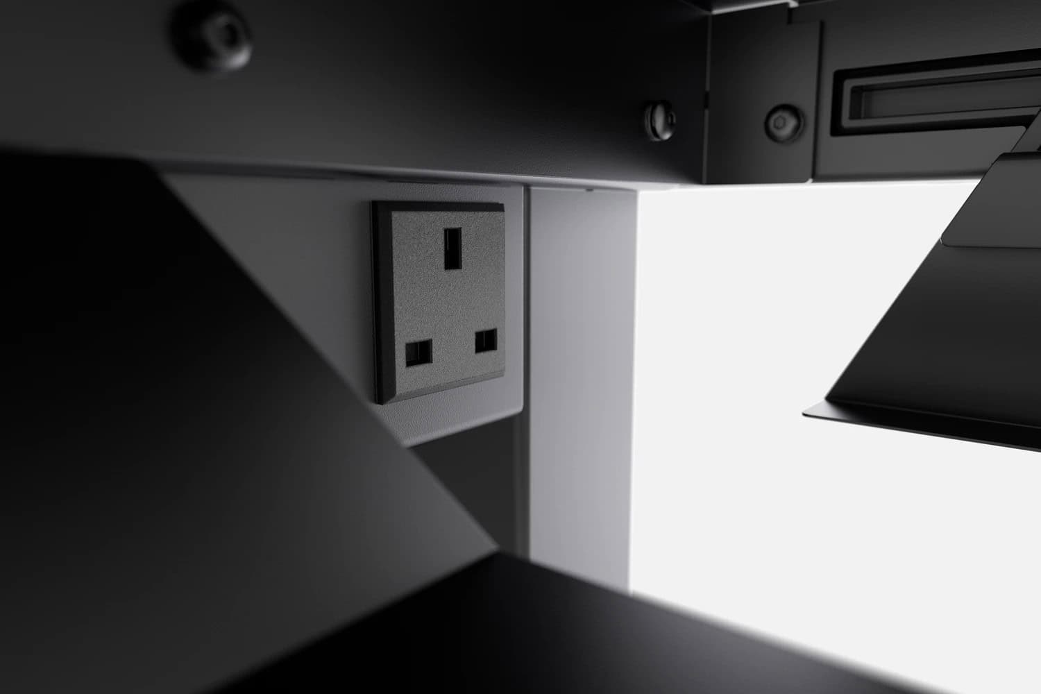 An electrical outlet on a white wall, partially shaded by geometric black shapes near a Secretlab Magnus Pro gaming desk.