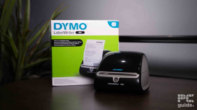 A Dymo LabelWriter 4XL label printer next to its packaging box on a desk with a blurred background.