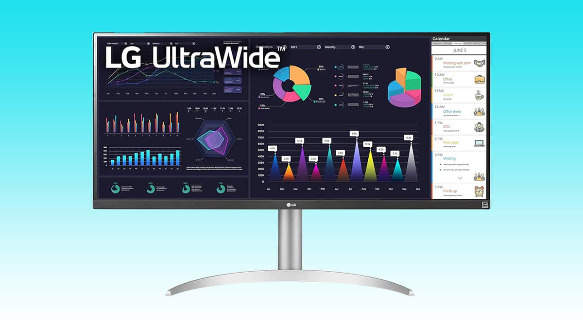 An ultrawide monitor displaying colorful graphs and business analytics on screen.