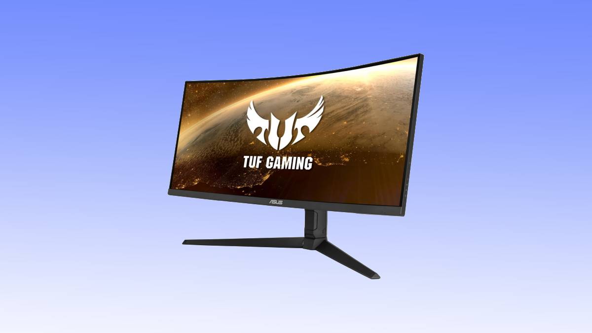Curved gaming monitor displaying a "tuf gaming" logo against a cosmic background, set on a black stand with a blue sky backdrop.