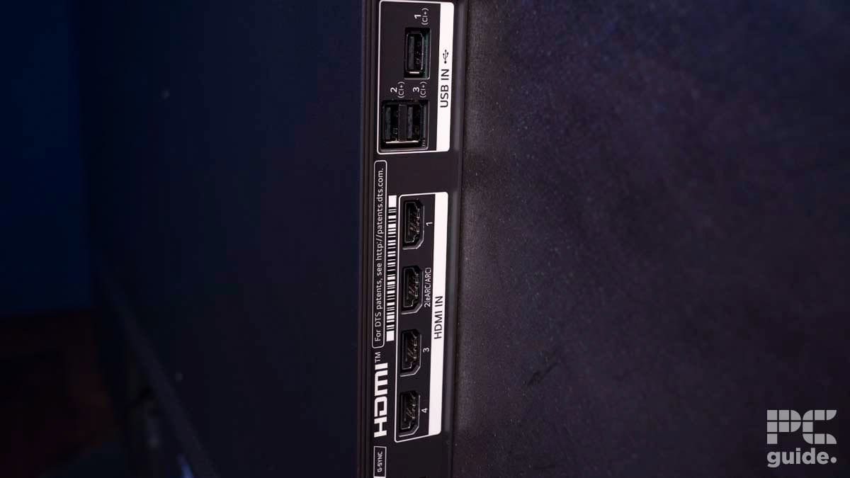 Close-up of a TV side panel showing multiple input ports: two HDMI IN ports, one Composite IN port, one Optical Digital Audio OUT port, and two USB IN ports. 