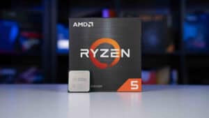 An AMD Ryzen 5 5600X processor box with a CPU chip in front, displayed against a blurred background of computer hardware shelves.