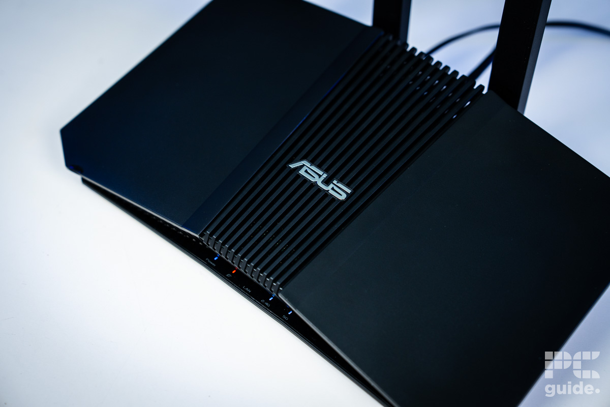 The black ASUS RT-BE58U (BE3600 router sitting on a white table shot from above. It shows the slope and white ASUS logo.