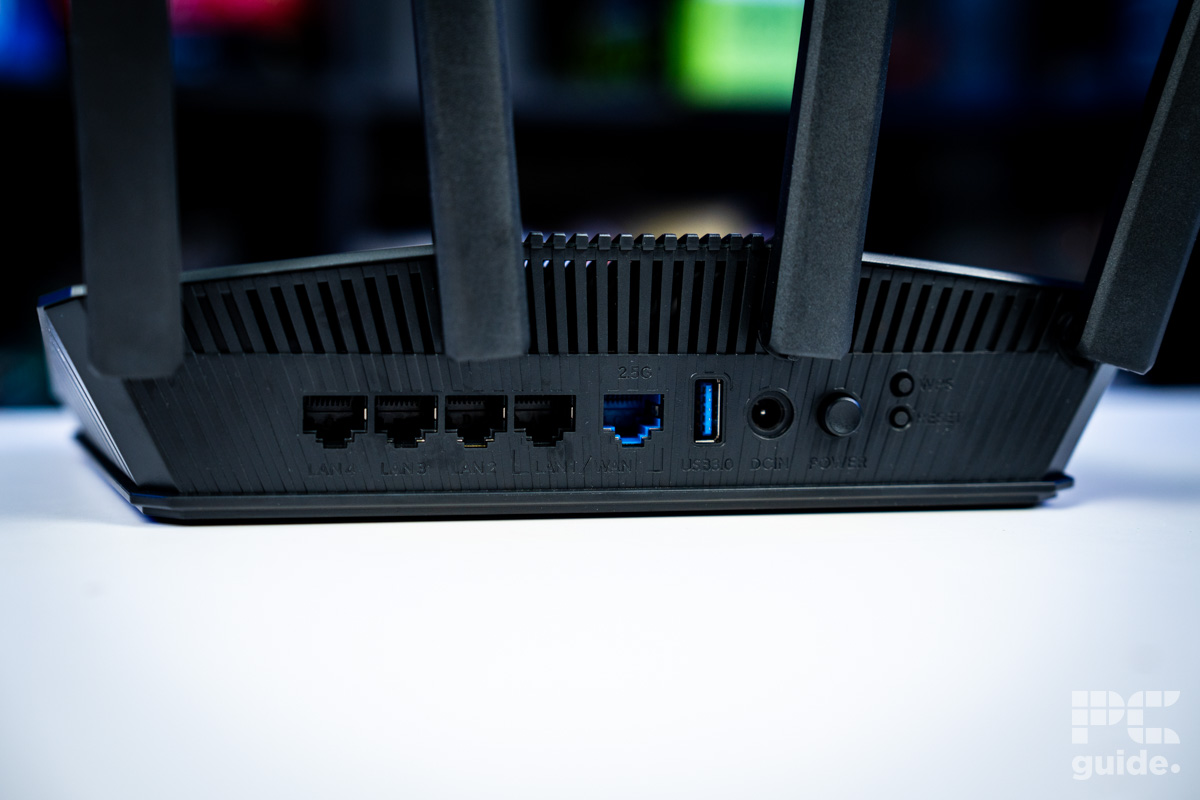 The rear of the black ASUS RT-BE58U (BE3600 router sitting on a white table.