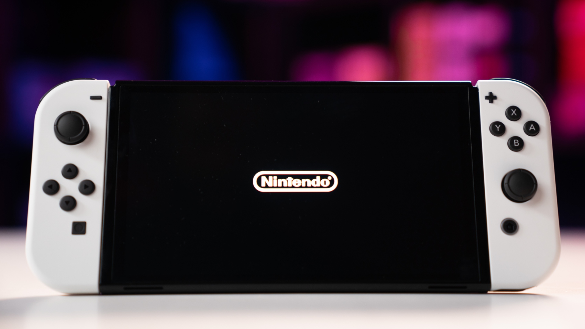 White Nintendo Switch OLED console in handheld mode displaying Nintendo logo, image by PC Guide