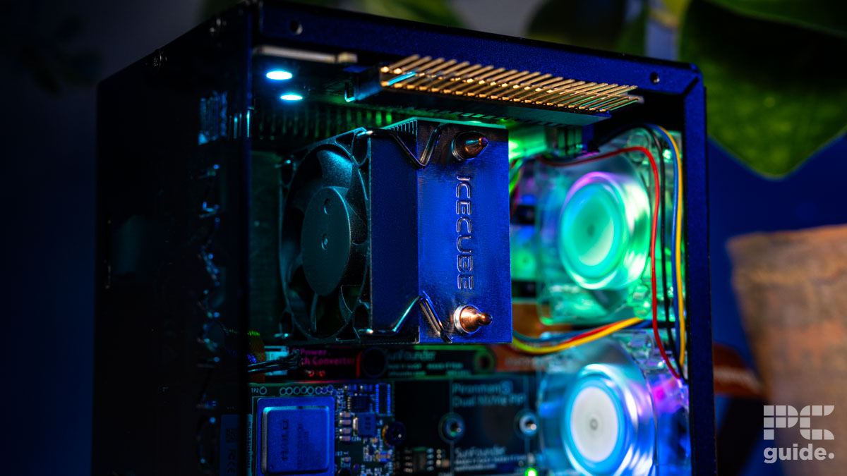The Pironman 5 Max case with components inside. It focuses on the cooler on top of the processor. Wiht fans in the background and PCIe board below.