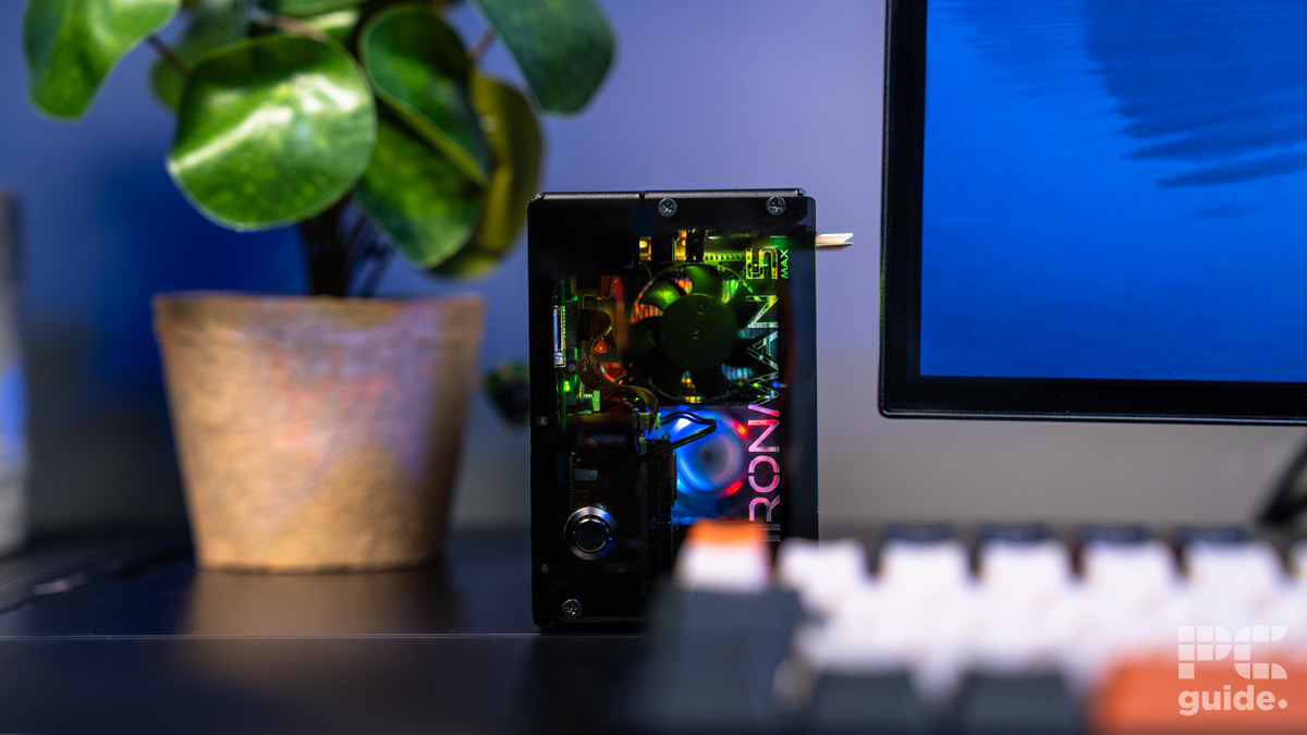 The Pironman 5 case built in the center and shown from the front. In the foreground is an out of focuse keyboard and monitor. In the back left is a plant.