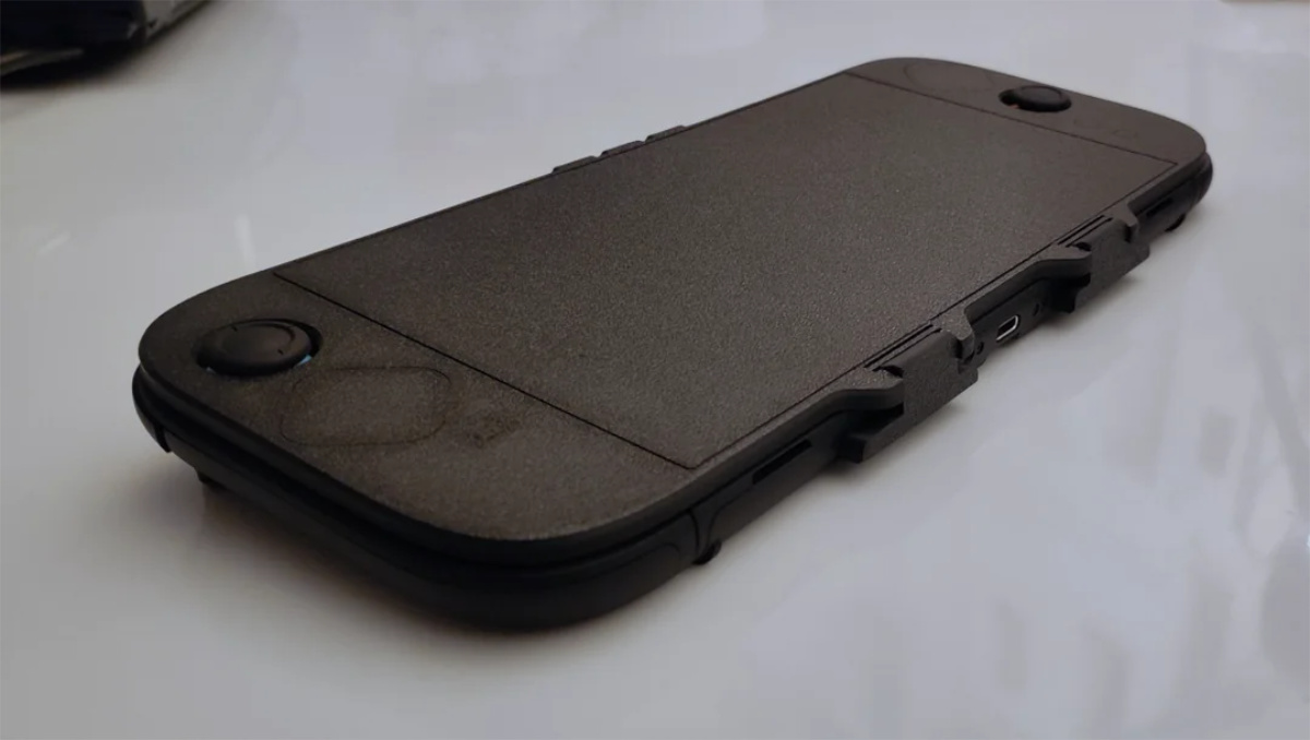 A clean white reflective suface. On top is a Switch 2 with the carry case protector that covers the whole front screen wiht just the joysticks poking out.