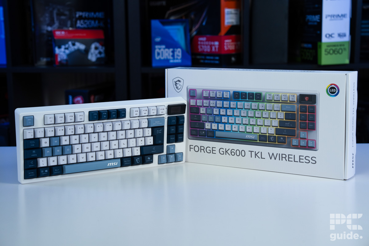 The MSI Forge GK600 TKL and its box on a white table with blurred PC componentns on a bookshelf behind.