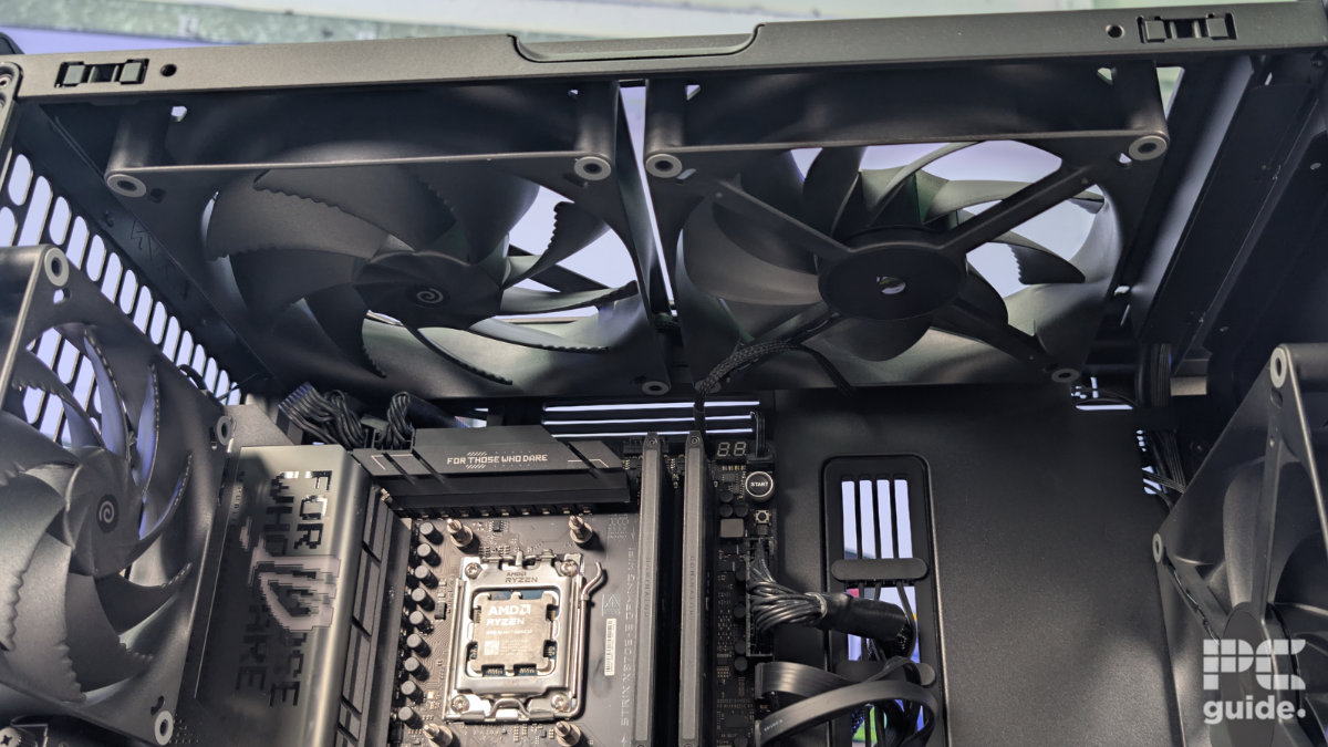 A inside view of the HAVN BF 360 case with the top taken off and a two 180mm fans installed. With the inside built wihth PC components, standing on a white desk with a background of PC component boxes on a bookshelf.