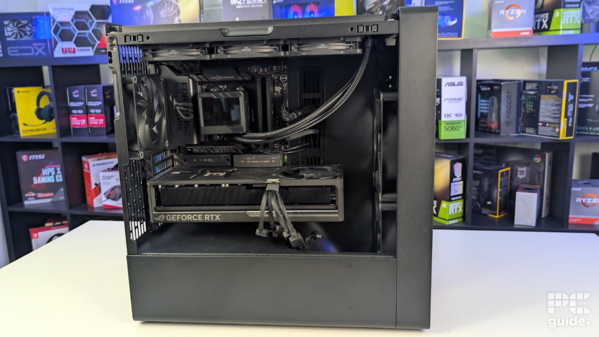 A view inside of the HAVN BF 360 standing on the white table and background of PC component boxes on a bookshelf. Inside the case is built wiht a GPU and AIO.