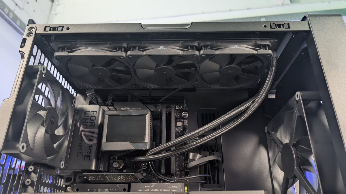 A inside view of the HAVN BF 360 case with the top taken off and a radiator installed for the AIO cooler. With the inside built wihth PC components, standing on a white desk with a background of PC component boxes on a bookshelf.