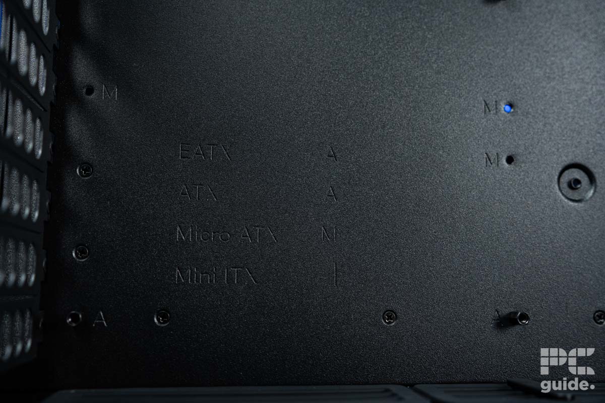A close up of the bottom left of the motherboard tray which features the acronyms for different motherboard sizing and where to place the standoffs for them.