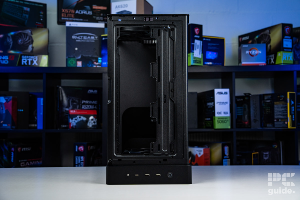 The HAVN BF 360 Flow placed on thw hwhite table front down with a background of PC component boxes on a booksheld. It shows the open top and peers into the case.