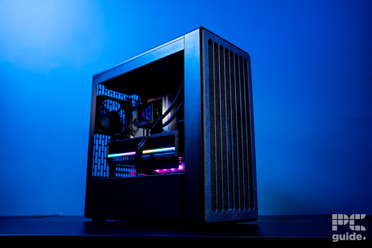 The HAVN BF 360 Flow case at an angle, with PC components inside. Sitting on a desk with a wall painted blue behind it.