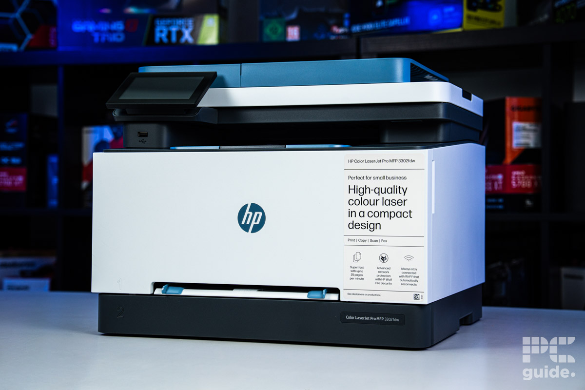The front of the HP Color LaserJet 3302fdw. Sitting on a white table, with a background of a bookshelf filled with PC component boxes.