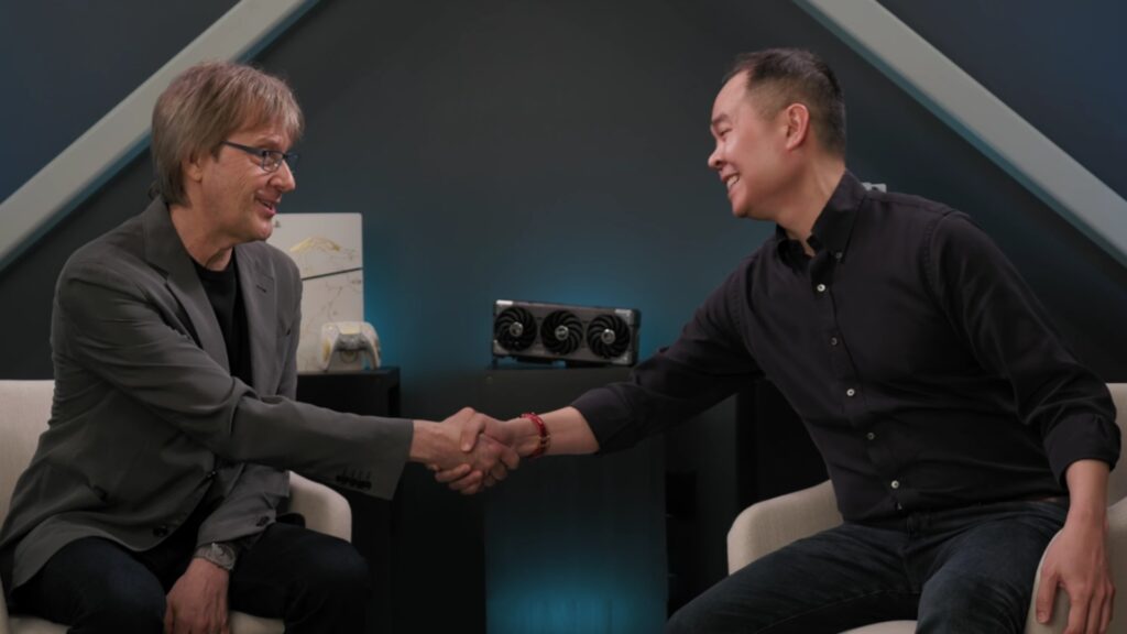Mark Cerny and Jack Huynh shaking hands with Radeon GPU and PS5 in background, credit: AMD