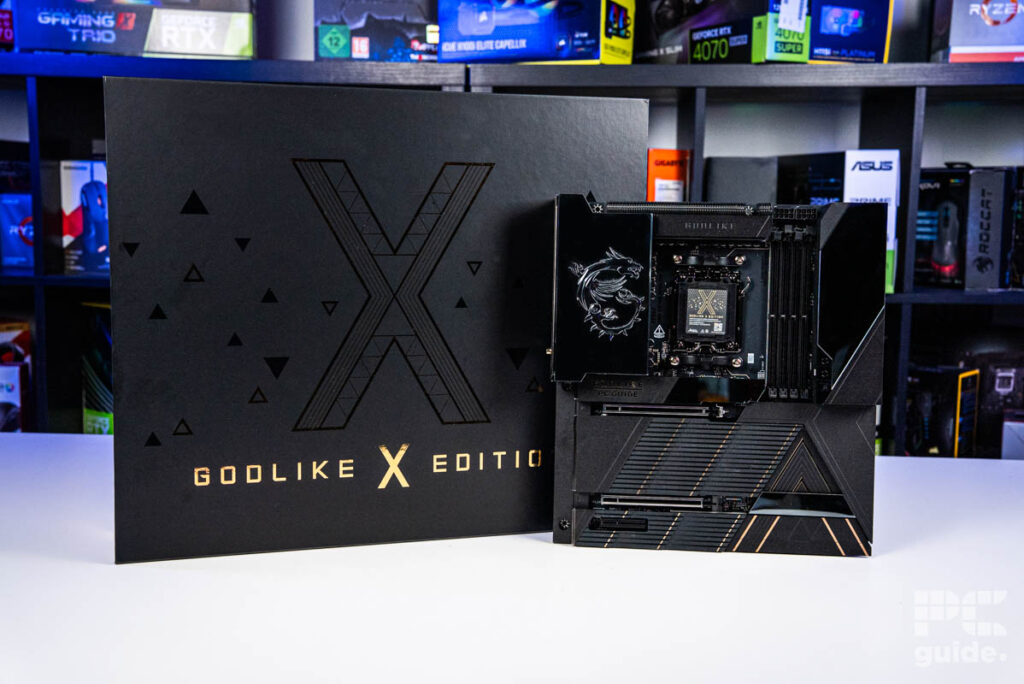 The MSI MEG X870E Godlike X Edition motherboard standing upright slightly to the right of its box both on a white table with a PC components on a bookshelf.